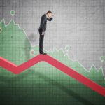 Businessman standing on falling diagram and peering into the future