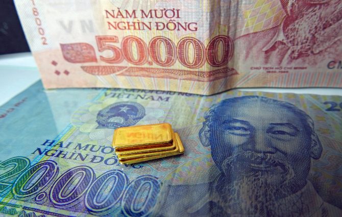 Kleine Goldbarren vor vietnamesischen Dong-Banknoten – Symbol für Marktöffnung